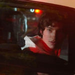 actor Ezra Miller looking out the back window of a Police car in WE NEED TO TALK ABOUT KEVIN movie