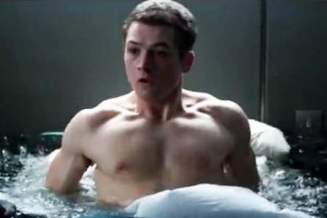 Kingsman movie: a shirtless Taron Egerton wakes up in bed with a pool of rising water surrounding him