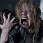 A frightened mother holding her young son close with her hand on the back of his head in The Babadook horror film