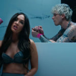 From music video "Bloody Valentine," actress Megan Fox sits by the bathtub with a blow dryer in hand while rapper Machine Gun Kelly is sitting inside the tub.