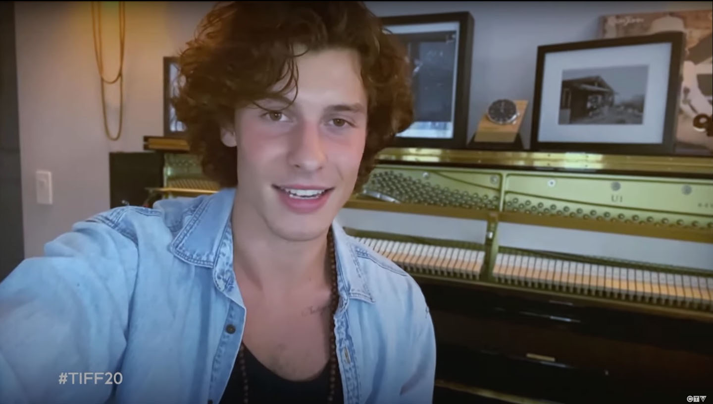 singer, Shawn Mendes sitting by the piano making an announcment on CTV and TIFF's tribute awards
