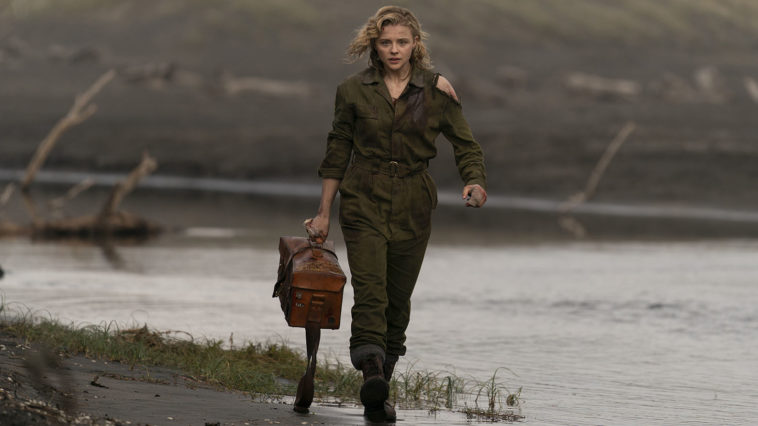 Actress Chloë Grace Moretz as a World War II pilot carries a medicine case walking in the field in this photo from SHADOW IN THE CLOUD film
