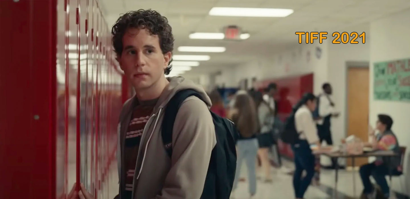 Standing by a row of school lockers. curly haired actor Ben Platt as high school student, Evan Hansen in Dear Evan Hansen movie