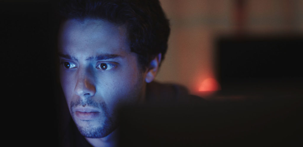 YouTuber turned actor Eric Tabach's face illuminated by what seems to be a computer screen in a still promo photo for DASHCAM, a thriller movie