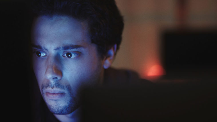 YouTuber turned actor Eric Tabach's face illuminated by what seems to be a computer screen in a still promo photo for DASHCAM, a thriller movie