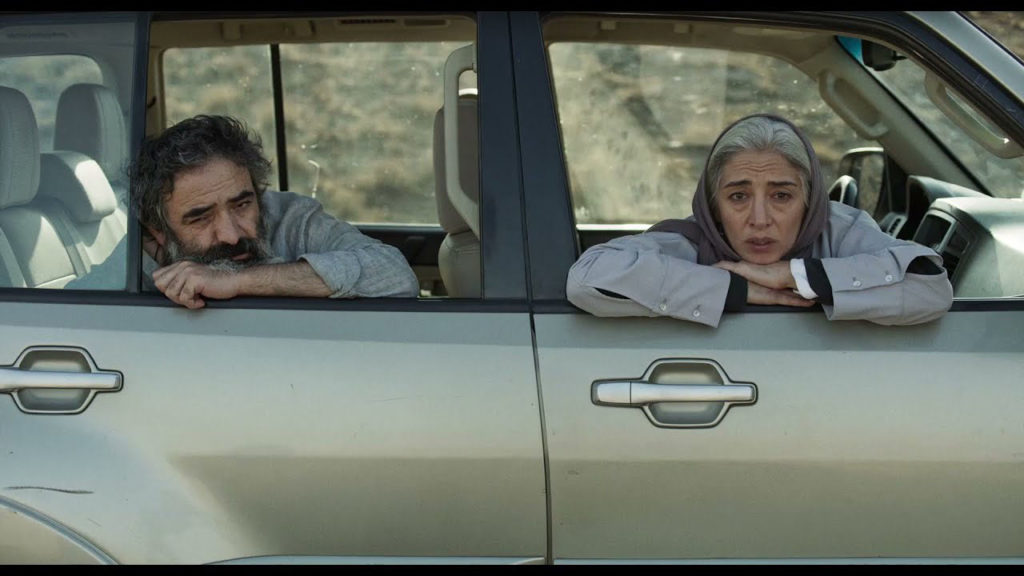 Worried parents, actor Hassan Madjooni and actress Pantea Panahiha look ahead from inside of the car in HIT THE ROAD Iranian film.
