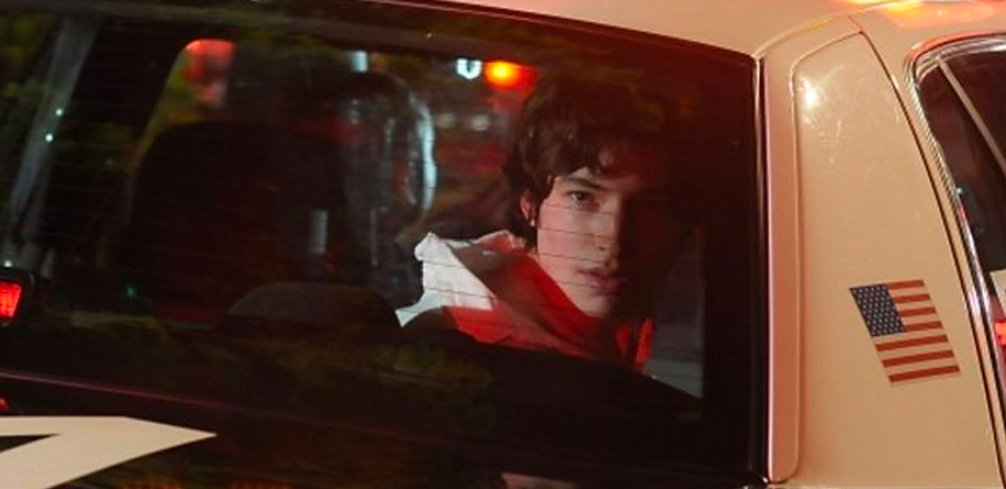 actor Ezra Miller looking out the back window of a Police car in WE NEED TO TALK ABOUT KEVIN movie